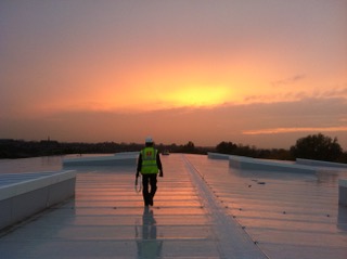 Man walking on a roof, sunset in the background