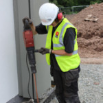 Man using large hand drill Surge and lightning protection installation for retail parks Scotland
